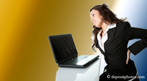 a person Baton Rouge  bending over a computer holding her back due to pain