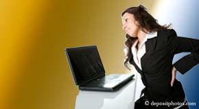 a person Baton Rouge bending over a computer holding her back due to pain